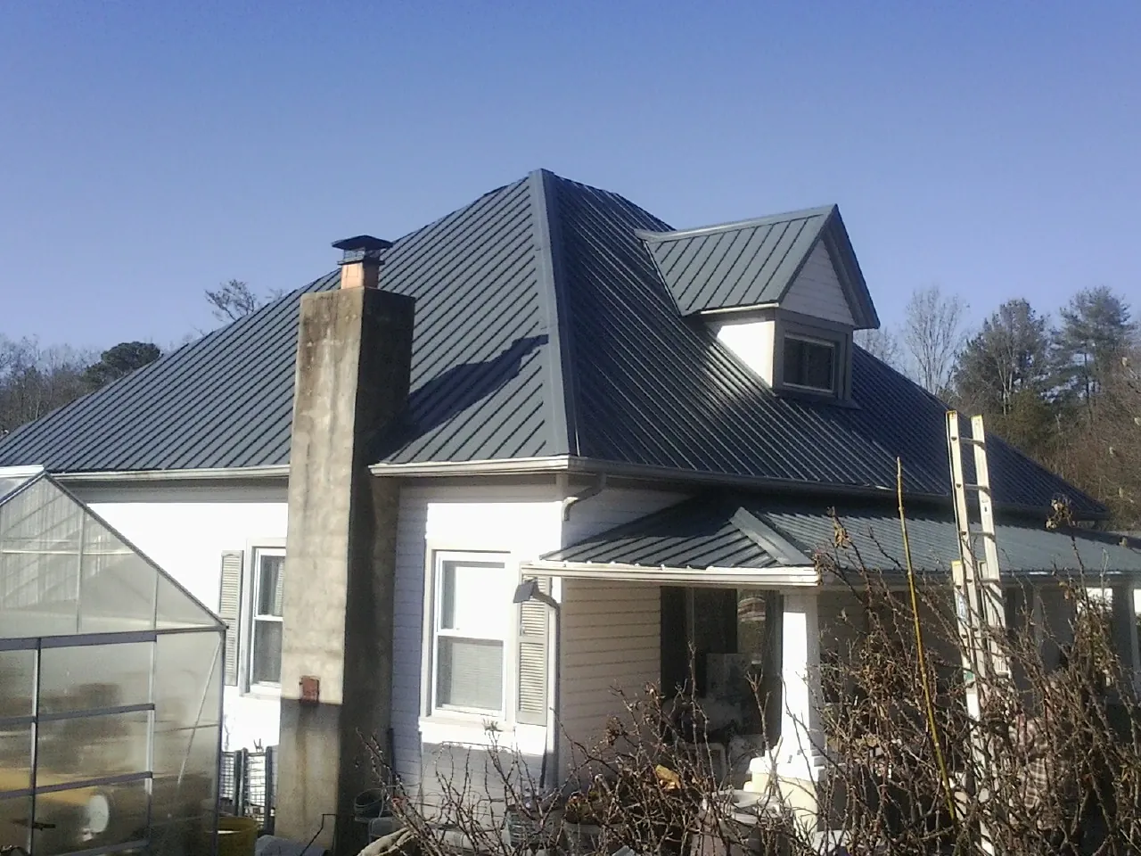 Dark blue standing seam metal roof on a white farmhouse with dormer — Slate & Tile Roof Repair by Roofing Brothers in Charlestown
