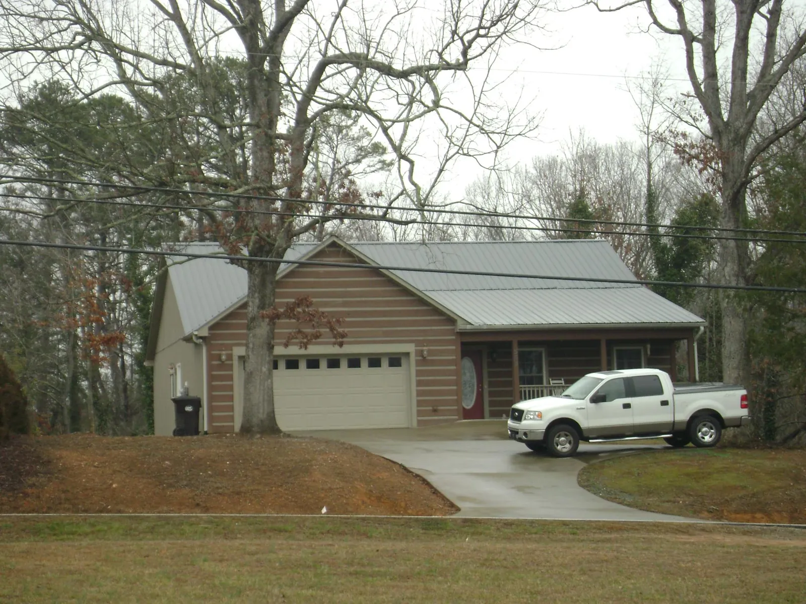 Gray metal roof on a log sided house with an attached two car garage in Charlestown